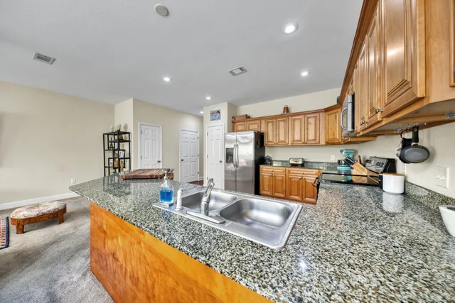 a kitchen with stainless steel appliances granite countertop a sink a stove and a wooden cabinets