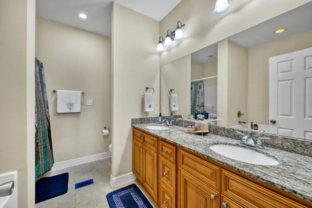 a bathroom with a granite countertop double vanity sink a mirror and a shower