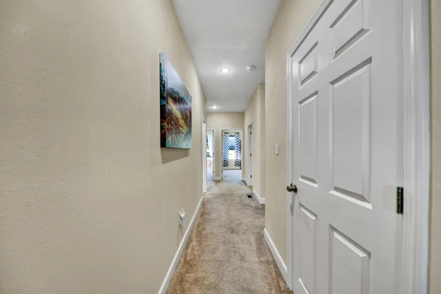 a view of a hallway with wooden floor and a bathroom