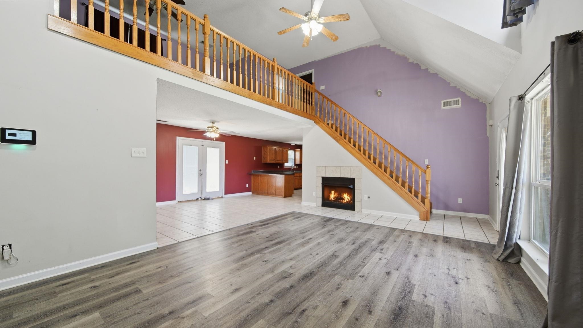 217 Rae Drive Munford, TN 38058 - Photo 8 of 40 Great room with vaulted ceilings featuring wood-finish flooring, a wood staircase and railing, and a tiled fireplace with gas logs.