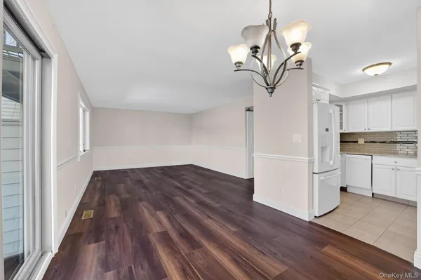 a view of kitchen with wooden floor electronic appliances and cabinets
