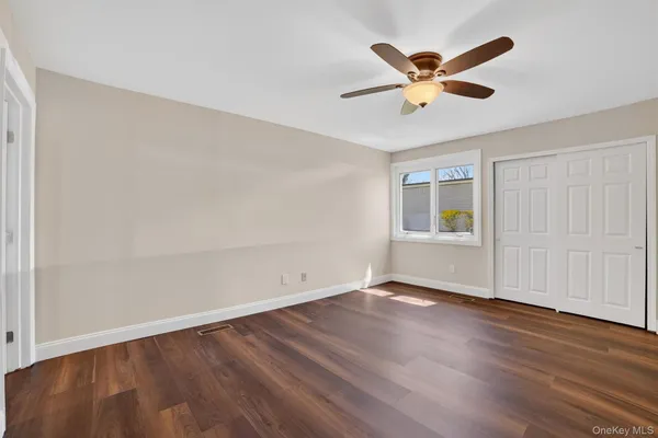 an empty room with wooden floor and ceiling fan