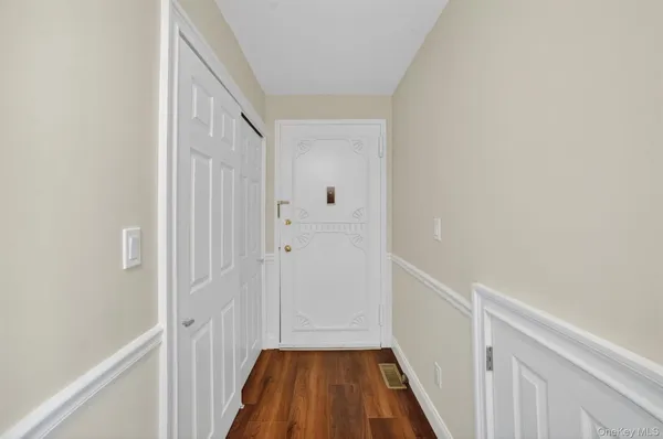 a view of a hallway with wooden floor and a bathroom