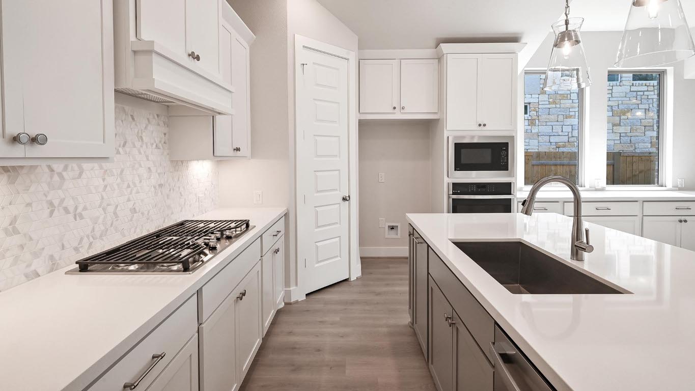 136 Brewer Street Kyle, TX 78640 - Photo 15 of 40 Kitchen featuring wood finished floors, stainless steel appliances, white cabinetry, backsplash, and decorative light fixtures