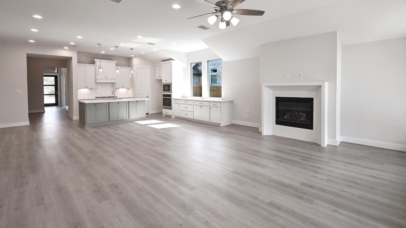 136 Brewer Street Kyle, TX 78640 - Photo 21 of 40 Unfurnished living room with light wood finished floors, a ceiling fan, recessed lighting, and a glass covered fireplace