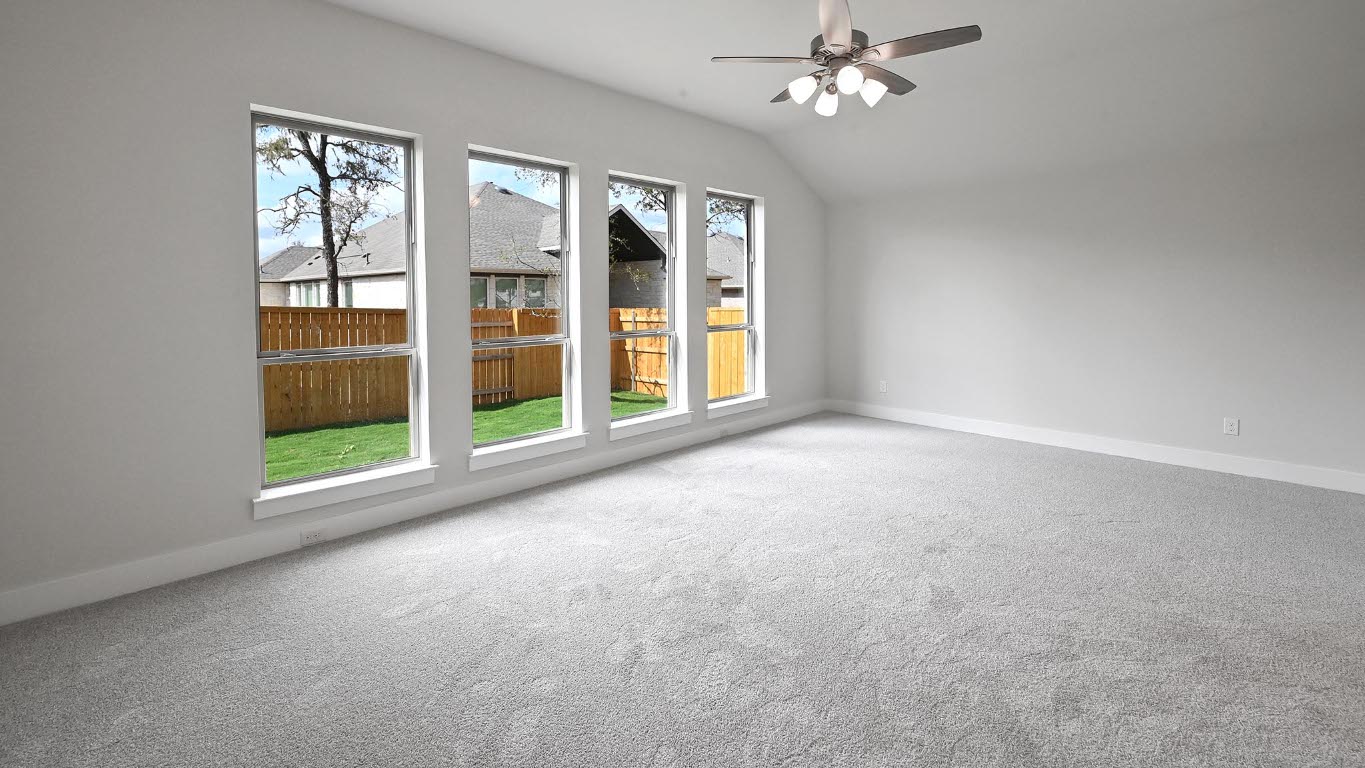 136 Brewer Street Kyle, TX 78640 - Photo 10 of 40 Empty room featuring light colored carpet, lofted ceiling, and ceiling fan