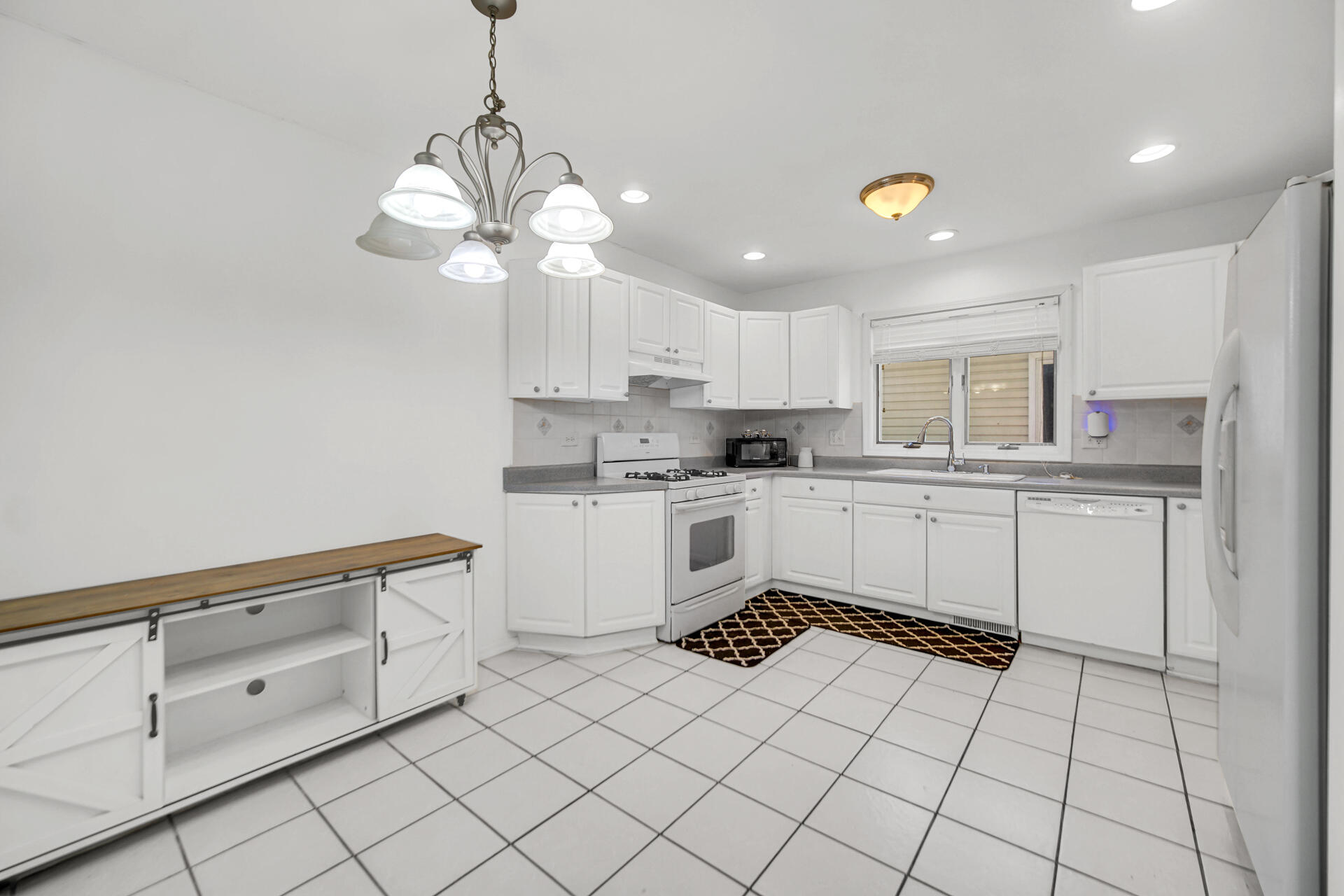 9993 Hunters Run St. John, IN 46373 - Photo 14 of 28 a kitchen with white cabinets a sink dishwasher and a stove with wooden floor