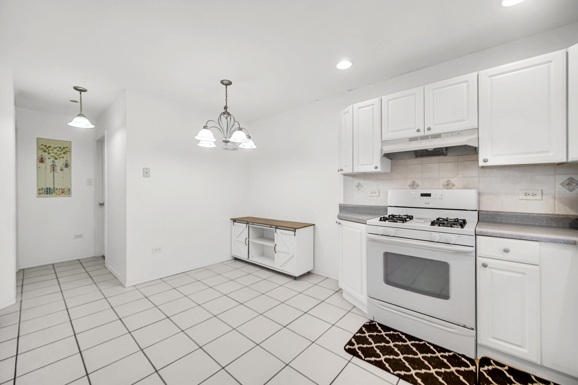 9993 Hunters Run St. John, IN 46373 - Photo 16 of 28 a kitchen with white cabinets a sink dishwasher and a stove with wooden floor
