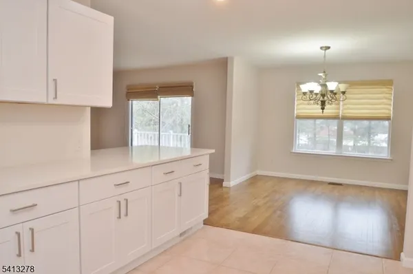 an empty room with chandelier fan and windows