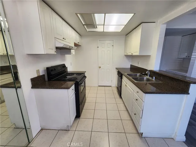 a kitchen with stainless steel appliances a refrigerator a sink dishwasher a stove and white cabinets with wooden floor