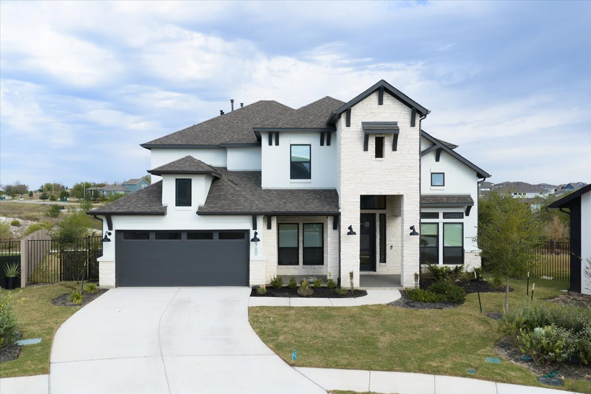8700 Olmsted Way Austin, TX 78744 - Photo 2 of 40 View of front of house featuring a shingled roof, driveway, a garage, stone siding, and stucco siding