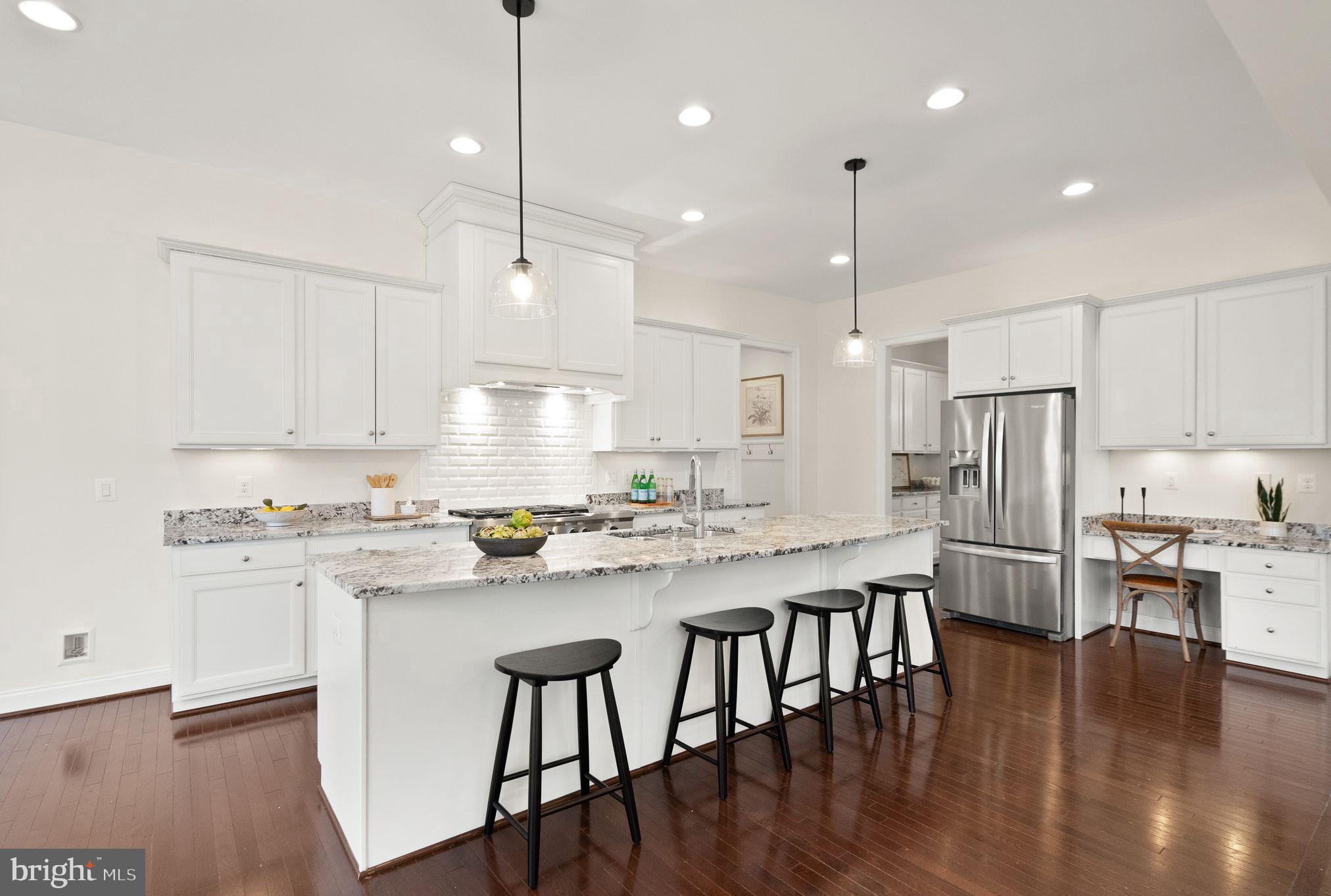 24974 First Harvest Court Aldie, VA 20105 - Photo 27 of 143 a kitchen with stainless steel appliances granite countertop a stove a refrigerator a kitchen island a sink and white cabinets with wooden floor