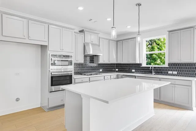 a kitchen with stainless steel appliances granite countertop a sink a stove and a refrigerator