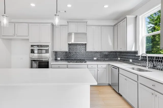 a kitchen with stainless steel appliances granite countertop a stove a sink and white cabinets