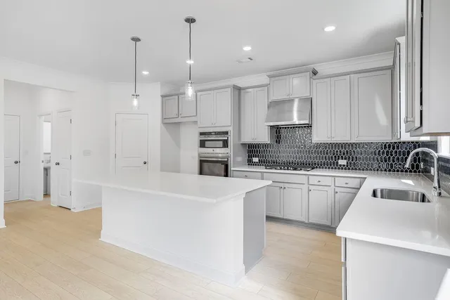 a large kitchen with stainless steel appliances kitchen island granite countertop a sink a stove and white cabinets
