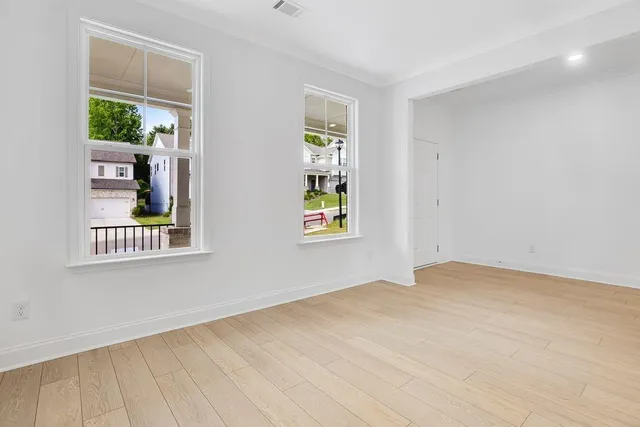 a view of an empty room with a window and wooden floor