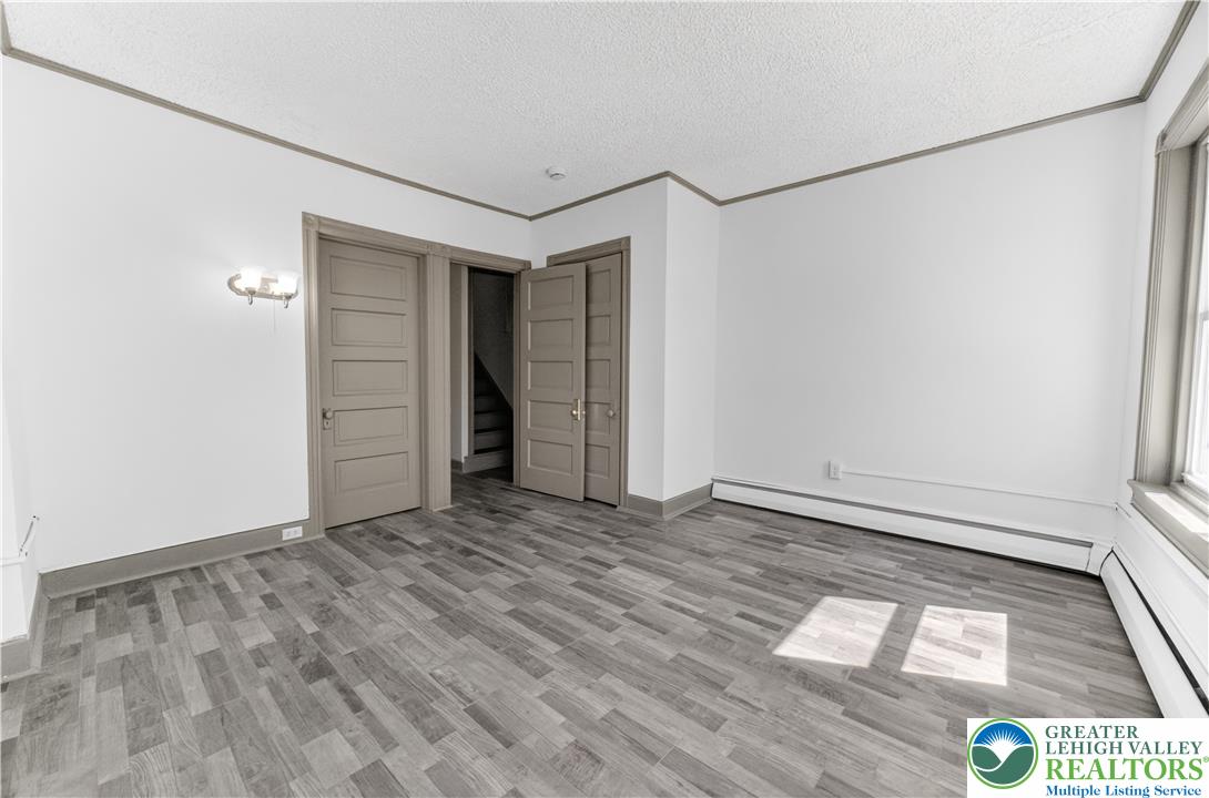 1128 Maple Street Bethlehem, PA 18018 - Photo 12 of 34 A well-lit room with modern plank flooring and convenient access to an interior staircase.
