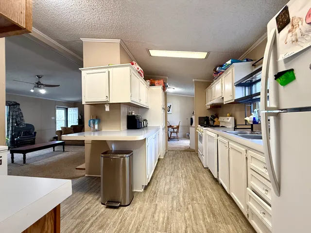 a kitchen with stainless steel appliances a stove a sink dishwasher a refrigerator white cabinets and wooden floor