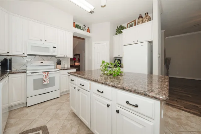 a kitchen with granite countertop white cabinets and white appliances