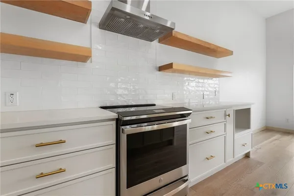 a kitchen with a white cabinets stove and wooden floor