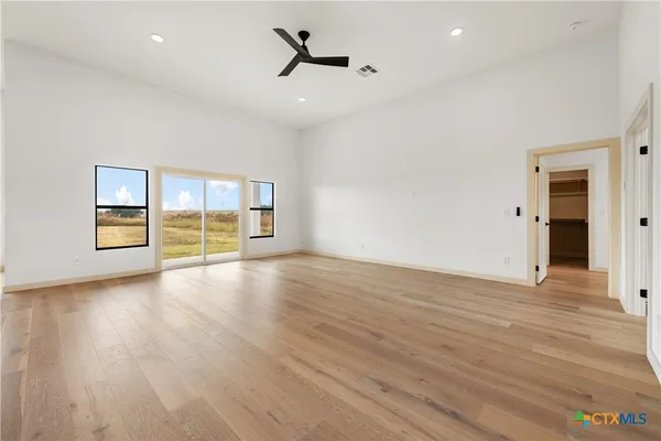 a view of empty room with wooden floor and fan