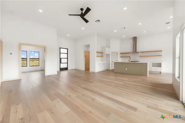 a view of kitchen and empty room with wooden floor and windows