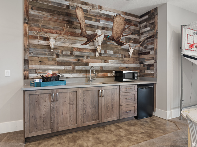 641 West 500 South Midway, UT 84049 - Photo 36 of 52 Custom wet bar featuring a paneled wood-finish accent wall, light grey countertops, a stainless steel sink with a gooseneck faucet, and integrated wood-finish cabinetry