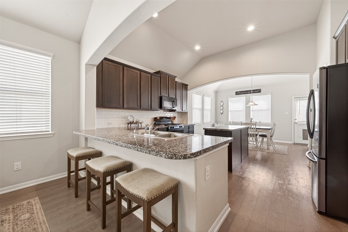 6027 Prince Place Drive Rosenberg, TX 77471 - Photo 12 of 39 Deep chocolate cabinets really pop against the white backsplash in the kitchen. The island and breakfast bar make this a natural spot for people to hang out while you cook.