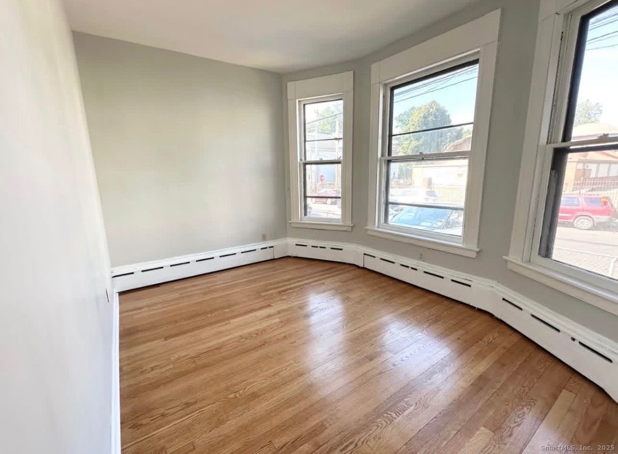 517 Colorado Avenue Bridgeport, CT 06605 - Photo 2 of 5 an empty room with wooden floor and windows