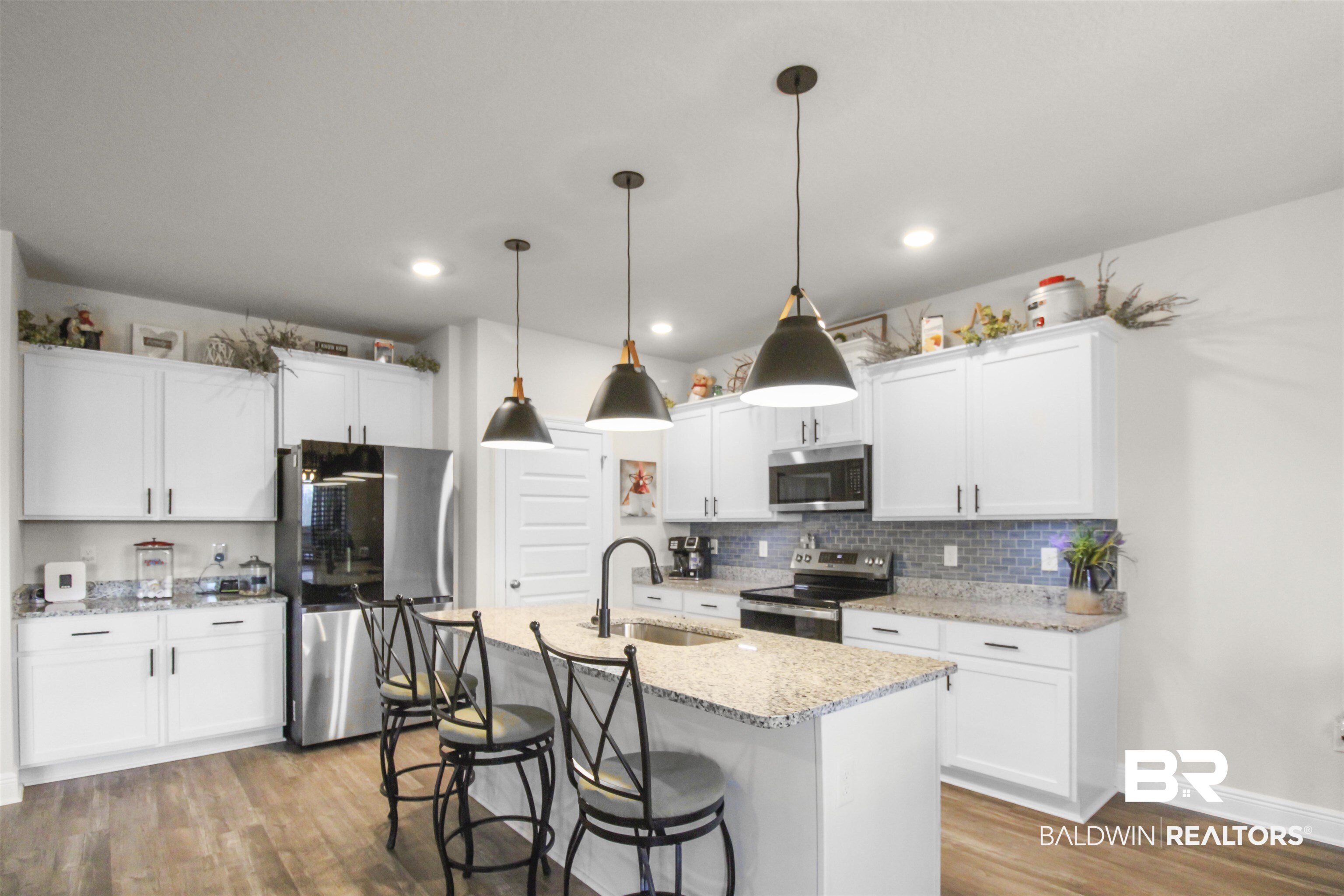 12523 Pheasant Run Elberta, AL 36530 - Photo 12 of 43 Kitchen with appliances with stainless steel finishes, a kitchen bar, white cabinetry, light stone countertops, and decorative light fixtures