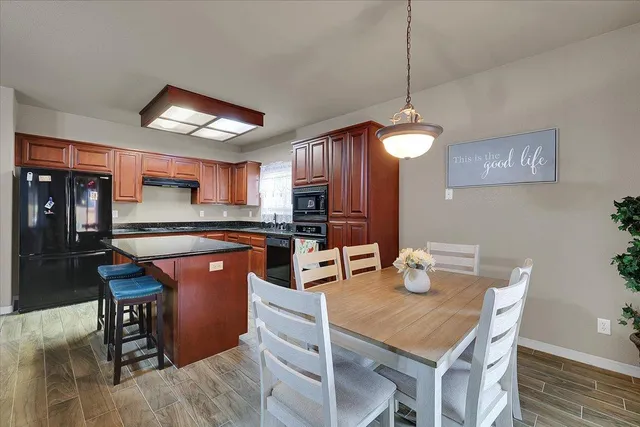 a kitchen with stainless steel appliances granite countertop a kitchen island hardwood floor sink stove dining table and chairs