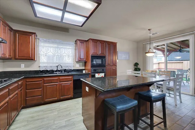 a kitchen with stainless steel appliances granite countertop a stove a sink dishwasher and cabinets with wooden floor