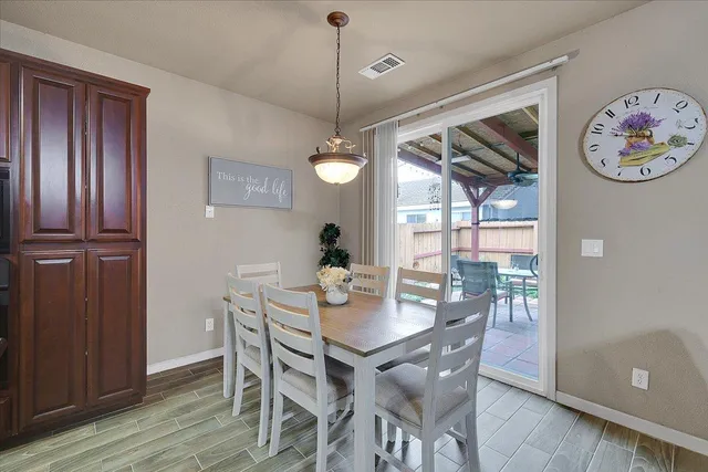 a dining room with wooden floor a chandelier a wooden table and chairs