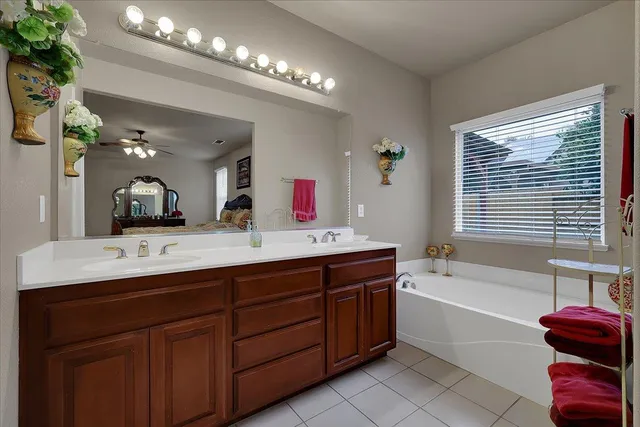 a bath room with a sink vanity tub and a mirror