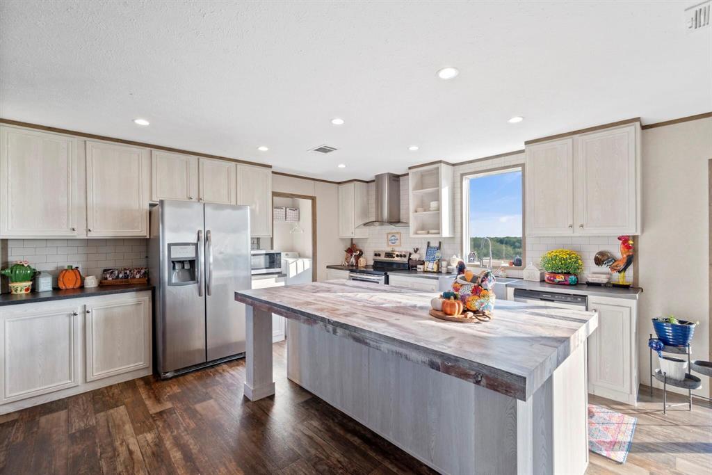 10026 County Rd NW 4350 Frost, TX 76641 - Photo 8 of 33 a kitchen with stainless steel appliances granite countertop a refrigerator a sink dishwasher a stove top oven a refrigerator and white cabinets with wooden floor