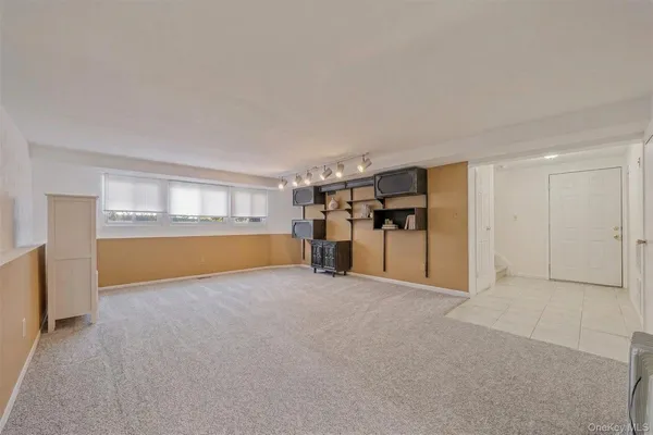 a view of an empty room with a window and kitchen view