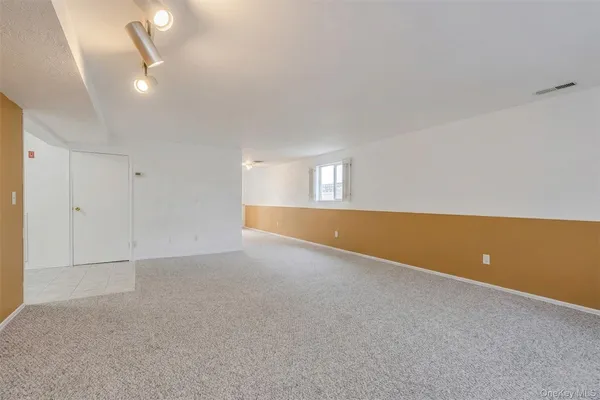 an empty room with chandelier fan and windows