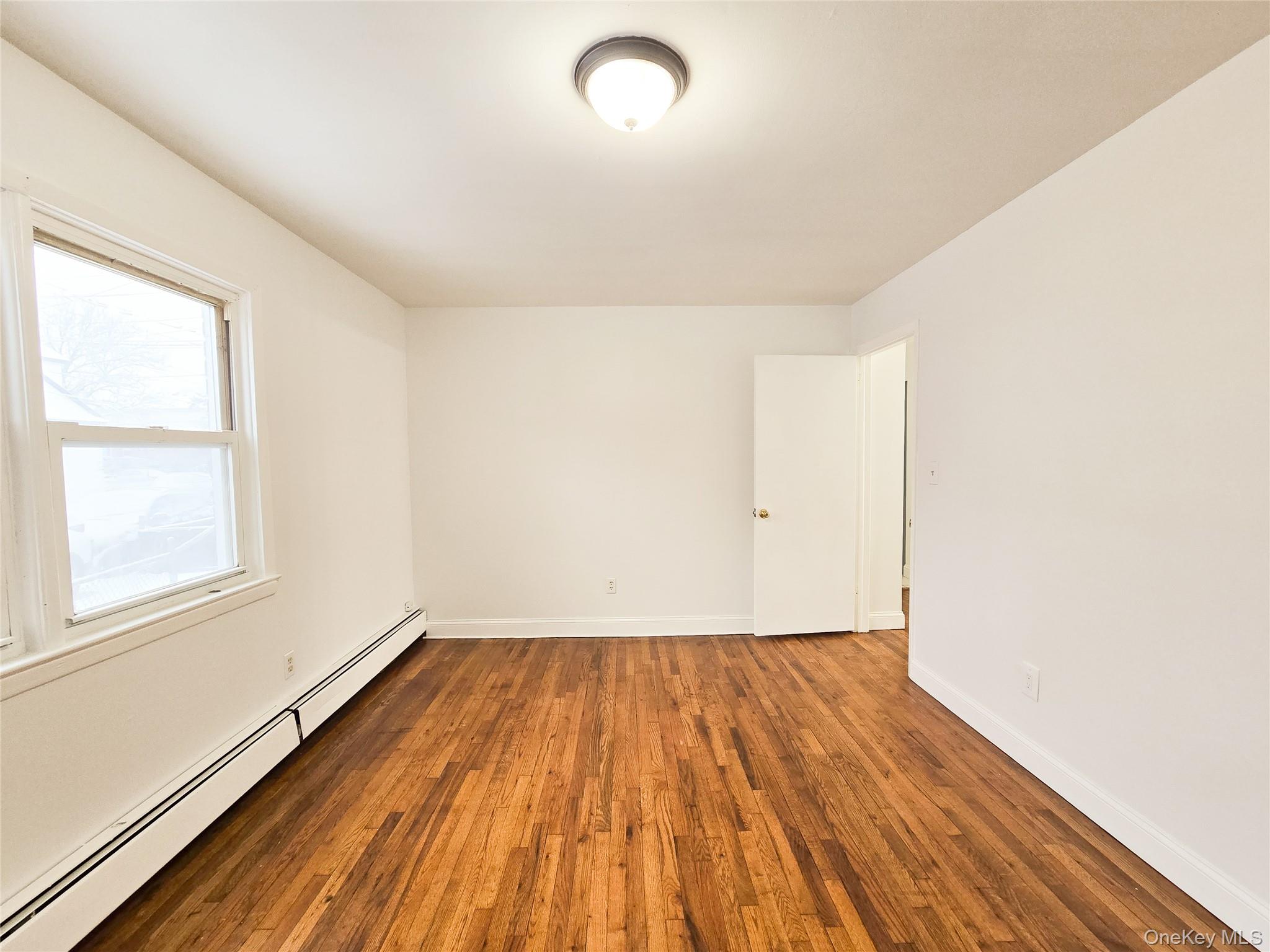 95-32 95th Street Queens, NY 11416 - Photo 4 of 20 an empty room with wooden floor and windows