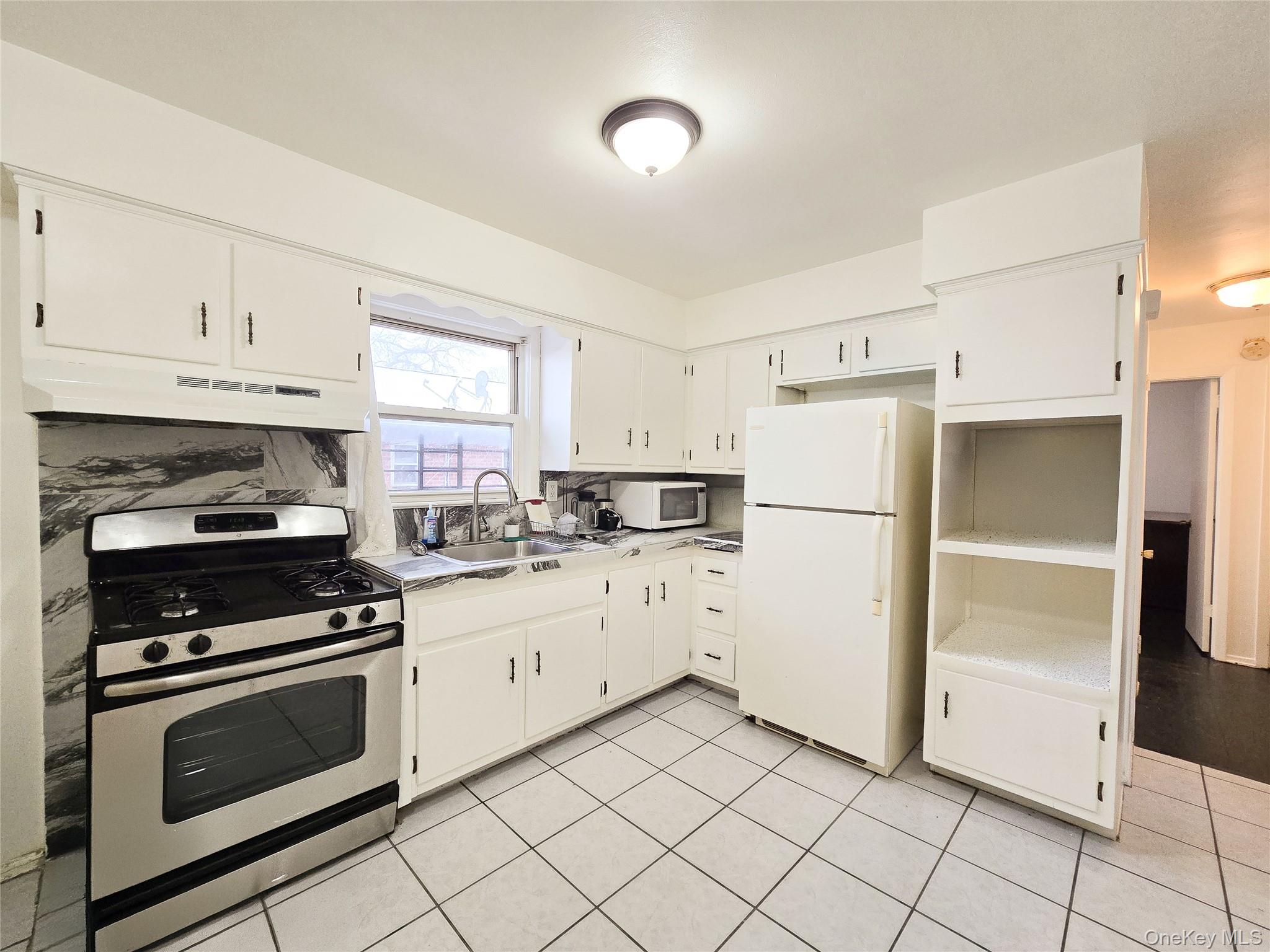 95-32 95th Street Queens, NY 11416 - Photo 5 of 20 a kitchen with cabinets stainless steel appliances and a window