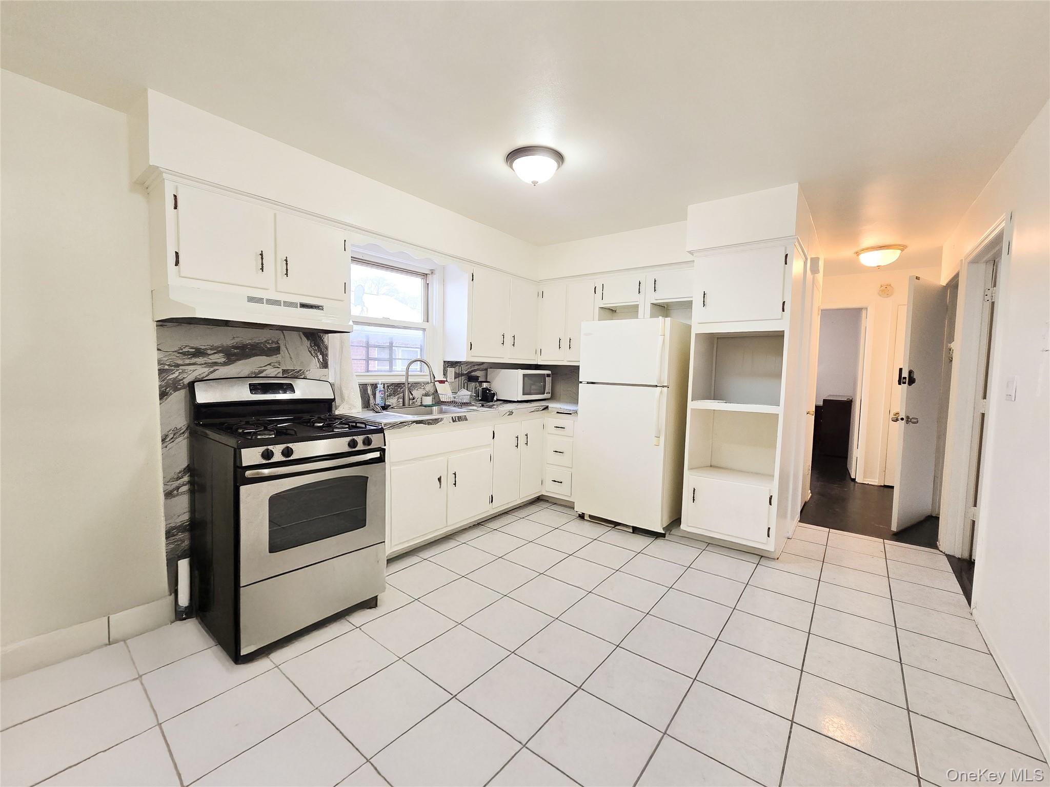 95-32 95th Street Queens, NY 11416 - Photo 8 of 20 a kitchen with white cabinets and white appliances