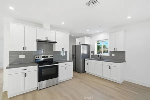a kitchen with stainless steel appliances a sink stove refrigerator and cabinets