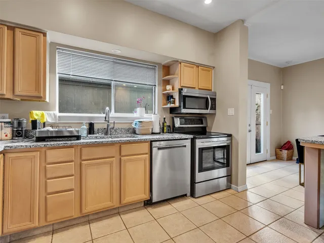 a kitchen with granite countertop a sink cabinets and stainless steel appliances
