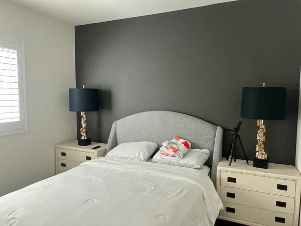 a bedroom with a bed and a lamp on dresser