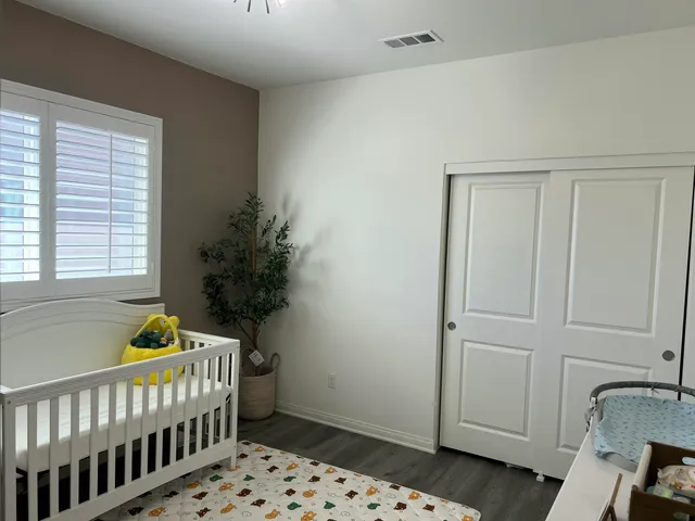 a room with baby crib and dresser