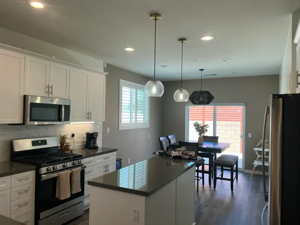 a kitchen with stainless steel appliances granite countertop a stove top oven a sink a dining table and chairs with wooden floor