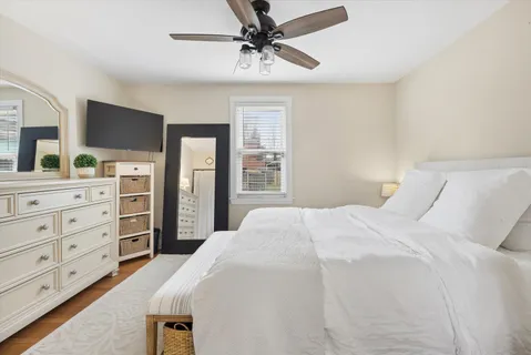a bedroom with a bed a dresser and a chandelier