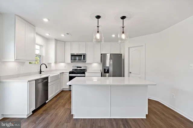 a kitchen with stainless steel appliances a microwave sink a refrigerator and white cabinets