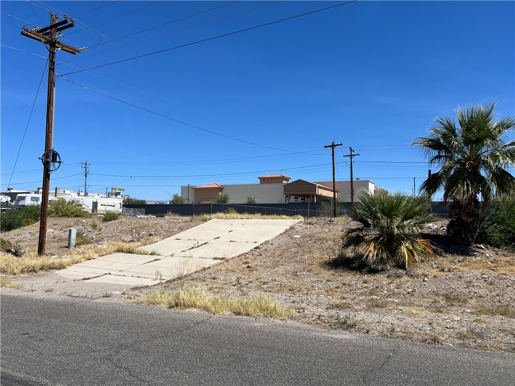1692 Shamrock Road Bullhead City, AZ 86442 - Photo 1 of 11 The property features a concrete driveway and sparse vegetation with palm trees