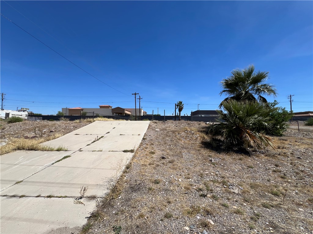 1692 Shamrock Road Bullhead City, AZ 86442 - Photo 4 of 11 The property features an unpaved lot with a concrete ramp and mature palm trees