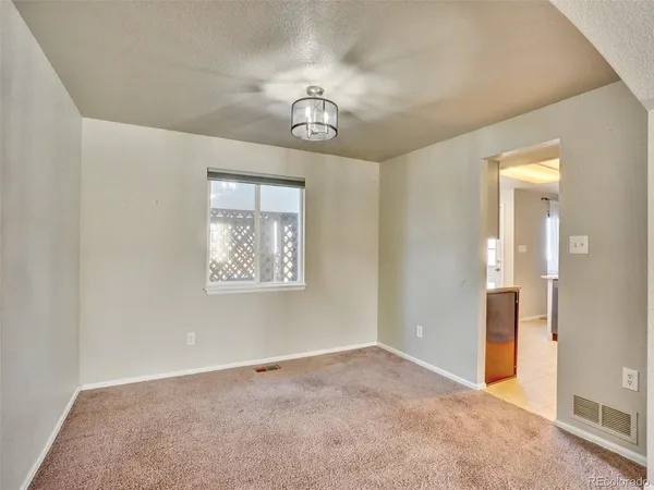 an empty room with a chandelier fan and windows